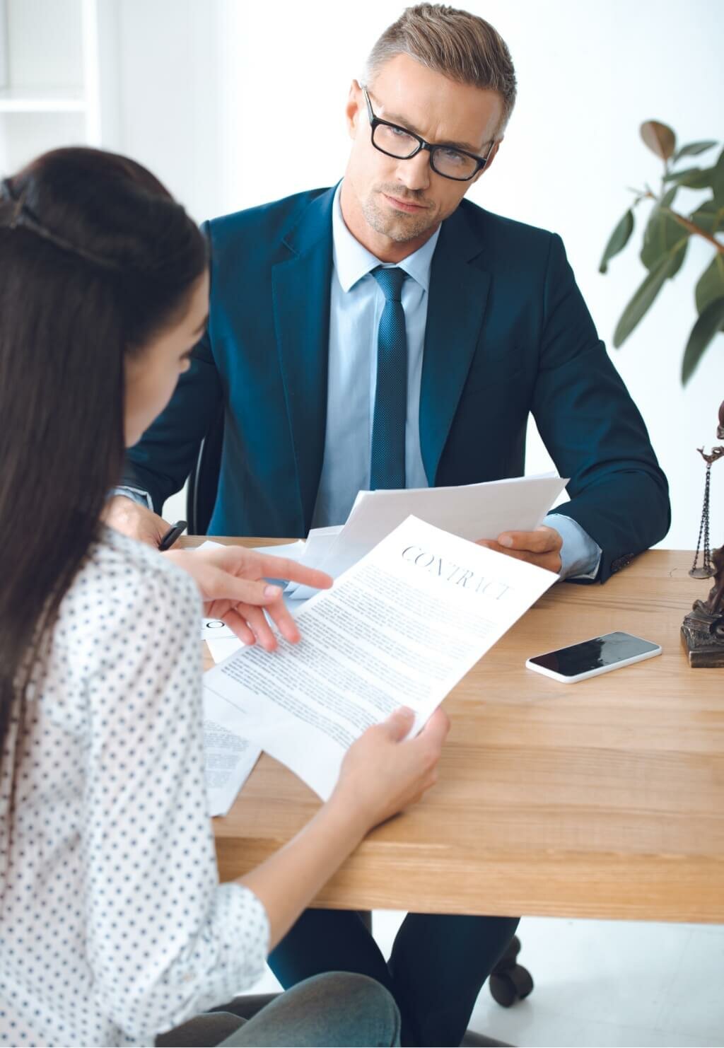 male lawyer looking at client reading contract QGN6KEA